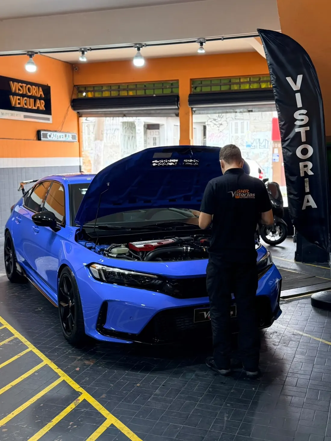 Vistoriador da GHR inspecionando o motor de um Honda Civic azul