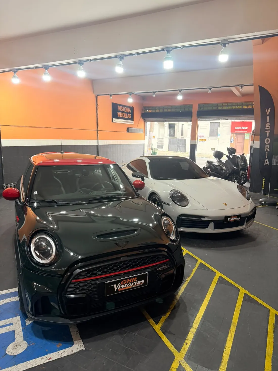 Mini Cooper verde e Porsche 911 branco na área de vistoria da GHR